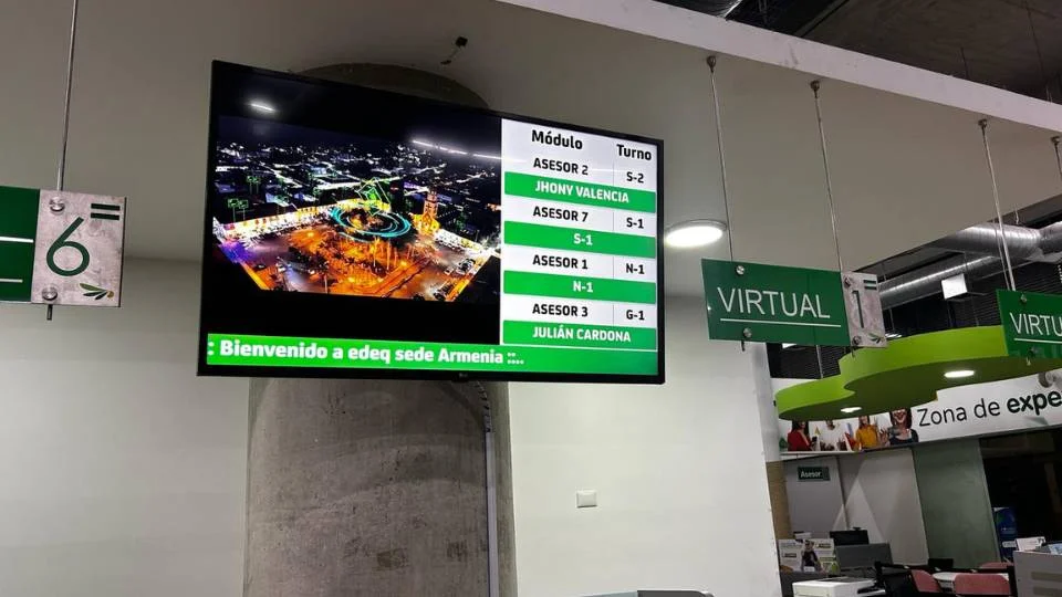 Monitor suspenso de grande formato mostrando claramente os módulos, a senha atual e os nomes dos agentes disponíveis