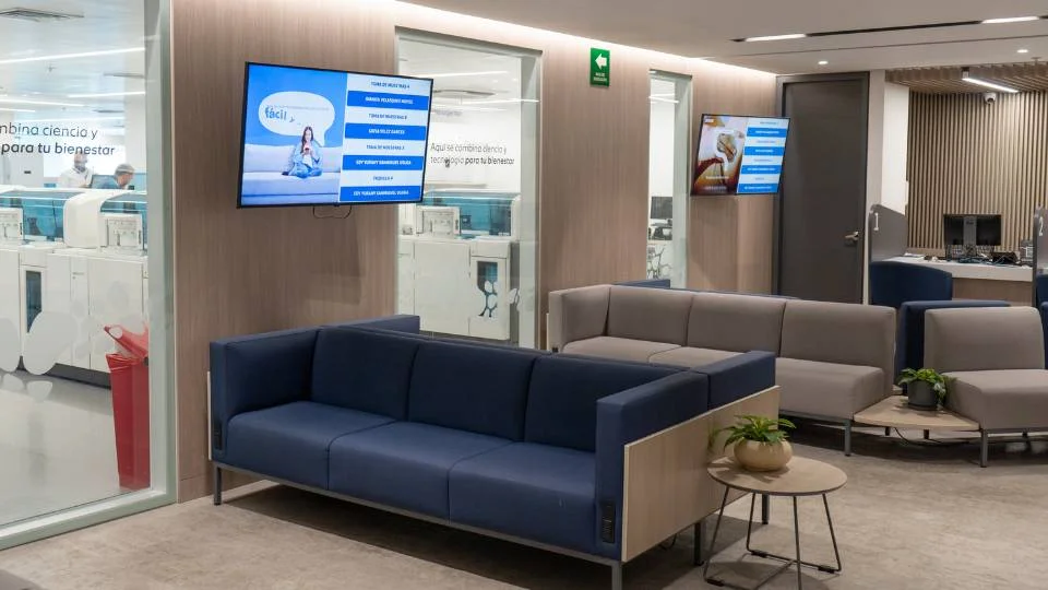 Sala de espera moderna e confortável equipada com telas informativas para acompanhamento do fluxo de atendimento